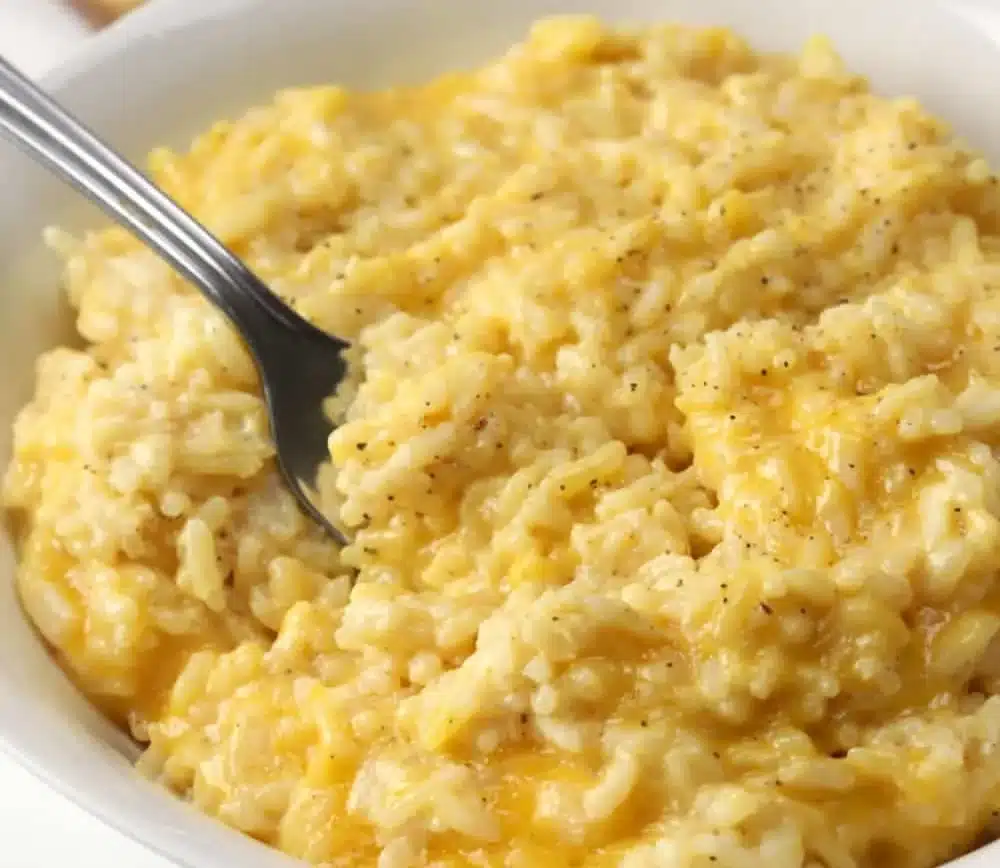 Creamy cheesy rice served in a bowl with herbs on top