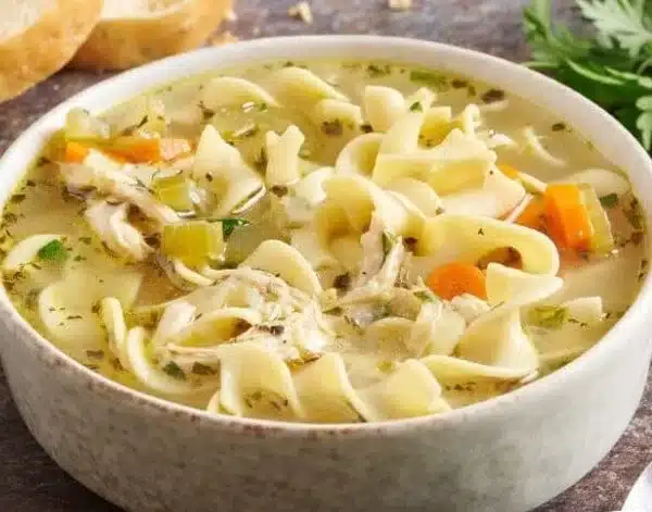 Bowl of soul-soothing chicken noodle soup with fresh ingredients and herbs