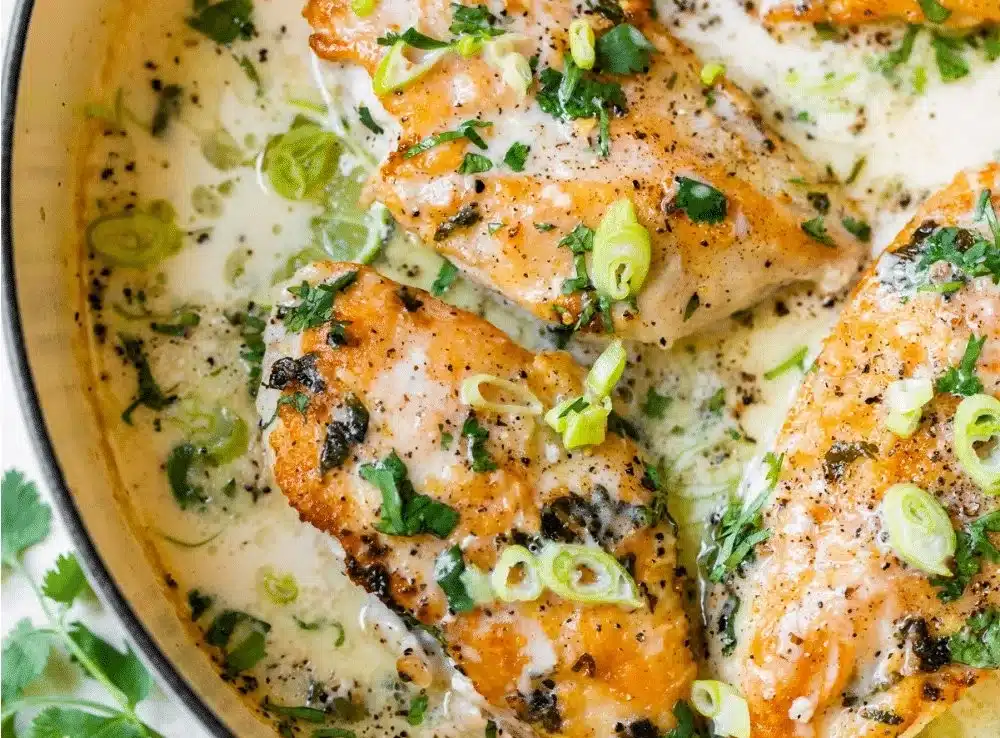 Creamy coconut lime chicken garnished with cilantro and served in a pan.